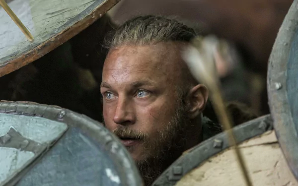 HD desktop wallpaper from the TV show Vikings (2013) featuring Ragnar Lothbrok peering through Viking shields in a tense moment.