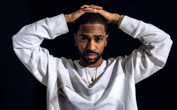 HD desktop wallpaper featuring a man in a white shirt, hands on head, with a black background.