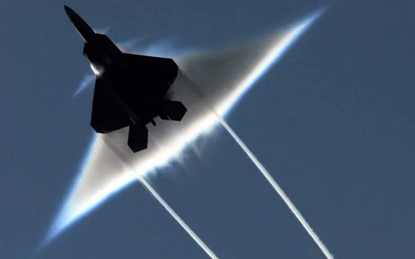 HD wallpaper of a Lockheed Martin F-22 Raptor military aircraft. The image captures the jet during supersonic flight, creating a vapor cone against a clear blue sky.