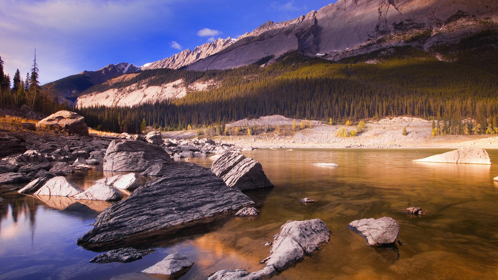 A serene landscape showcasing majestic mountains and calm water, surrounded by lush greenery, creating a breathtaking natural scene for an HD desktop wallpaper.