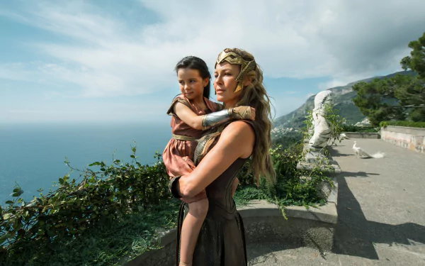 General Antiope (Robin Wright) holds a young girl against a scenic coastal backdrop in a HD desktop wallpaper from the movie Wonder Woman.