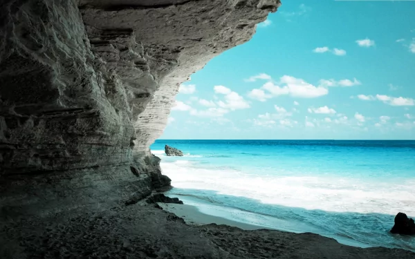 A stunning HD wallpaper depicting a serene cave by the beach, showcasing crystal-clear water and a vibrant sky, inviting you to explore the beauty of nature.