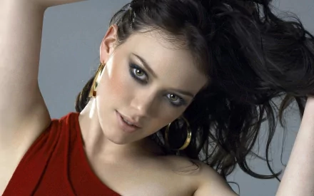 Stunning HD wallpaper featuring celebrity Hilary Duff, showcasing her in a stylish red top and striking earrings, with her hair elegantly flowing.