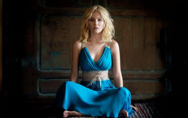 HD desktop wallpaper featuring celebrity Elisha Cuthbert, dressed in a blue gown, sitting against a rustic wooden background.