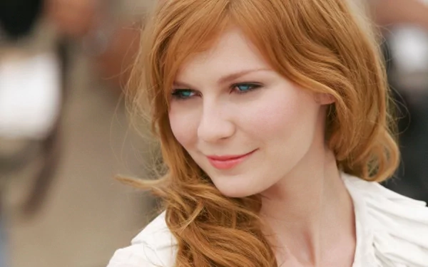 A captivating HD desktop wallpaper featuring celebrity Kirsten Dunst with her signature red hair and a charming smile, exuding elegance and warmth.