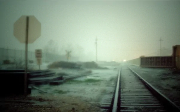 A moody, atmospheric image of a railyard at dusk, featuring blurred railroad tracks fading into the mist, creating a hauntingly beautiful desktop wallpaper.