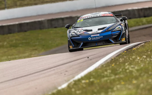 Front view of a McLaren 570S GT4 race car, a high-performance supercar vehicle charging down a racetrack — rendered as a 2K Quad HD PC desktop wallpaper.