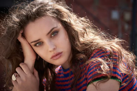 HD desktop wallpaper featuring Australian actress Katherine Langford. The brunette celebrity with blue eyes poses thoughtfully, wearing a striped shirt.