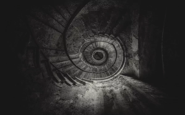 Black and white 4K Ultra HD image of a man-made spiral staircase viewed from above, highlighting the intricate curvature and textured stairs in dramatic light and shadow.