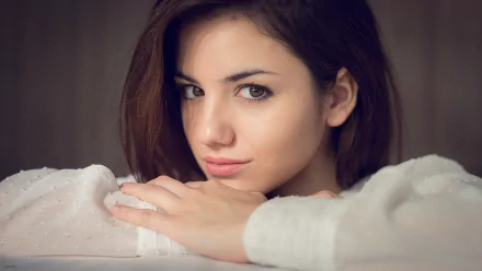 HD desktop wallpaper featuring a close-up portrait of a woman with short brown hair resting her chin on her hands, tagged Delaia Gonzalez.
