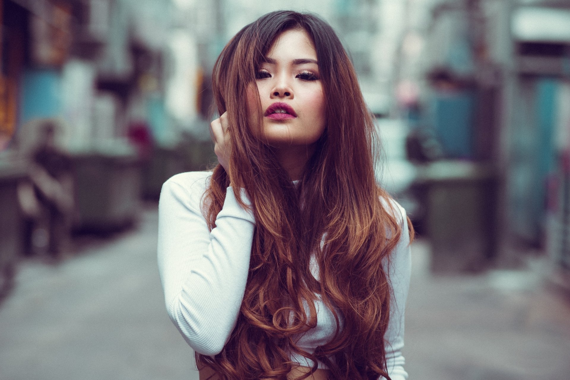Brunette model wearing lipstick, posed on an urban street with shallow depth of field — 4K Ultra HD PC desktop wallpaper and background.
