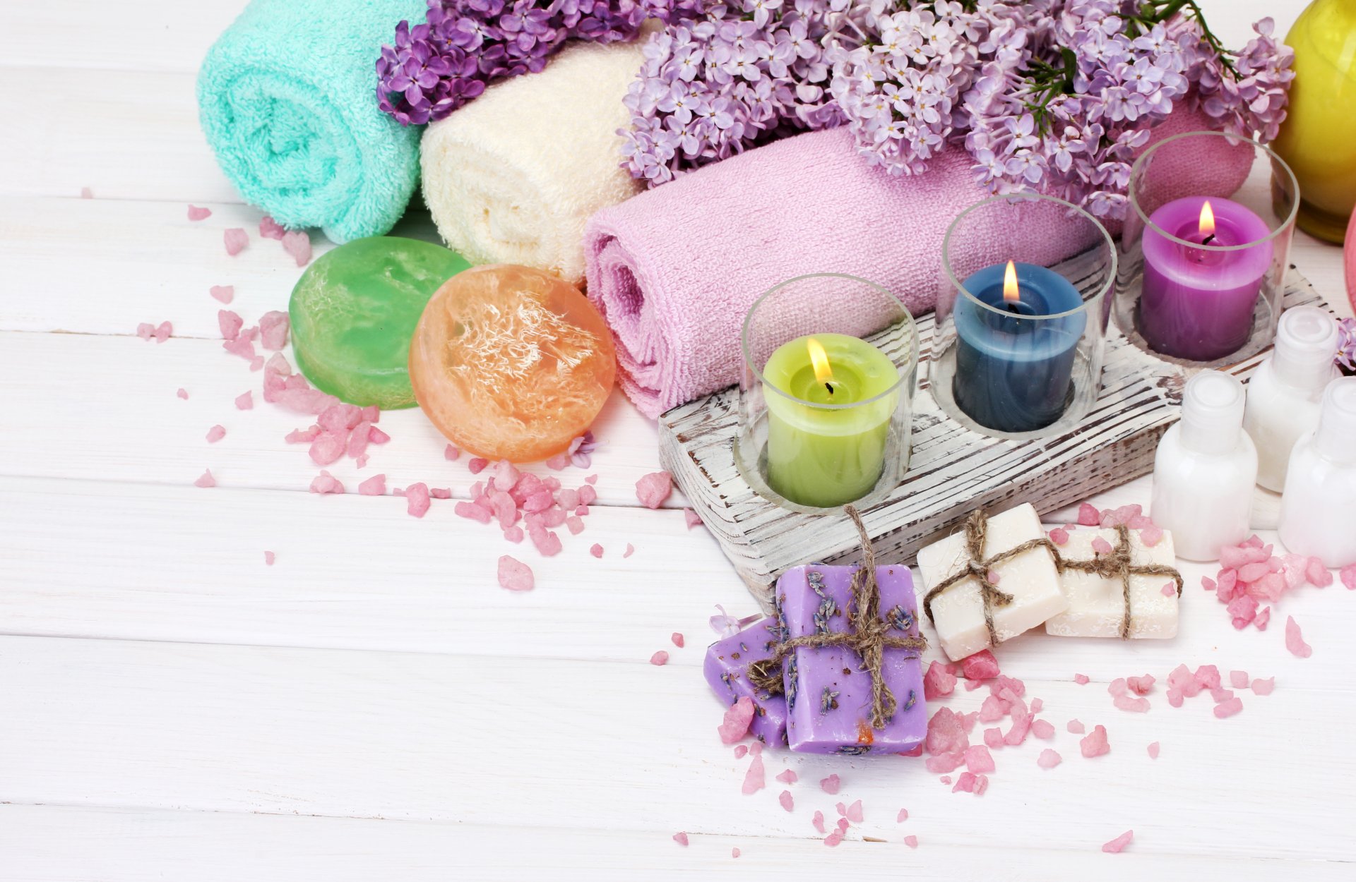 A serene 4K Ultra HD spa scene with rolled towels, lit candles, soaps, and floral accents, evoking a calming, zen atmosphere.