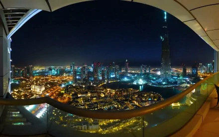 HD desktop wallpaper of Dubai at night, showcasing the city's stunning skyline illuminated with vibrant lights against a dark sky. The image captures man-made wonders and an urban landscape from a high vantage point.
