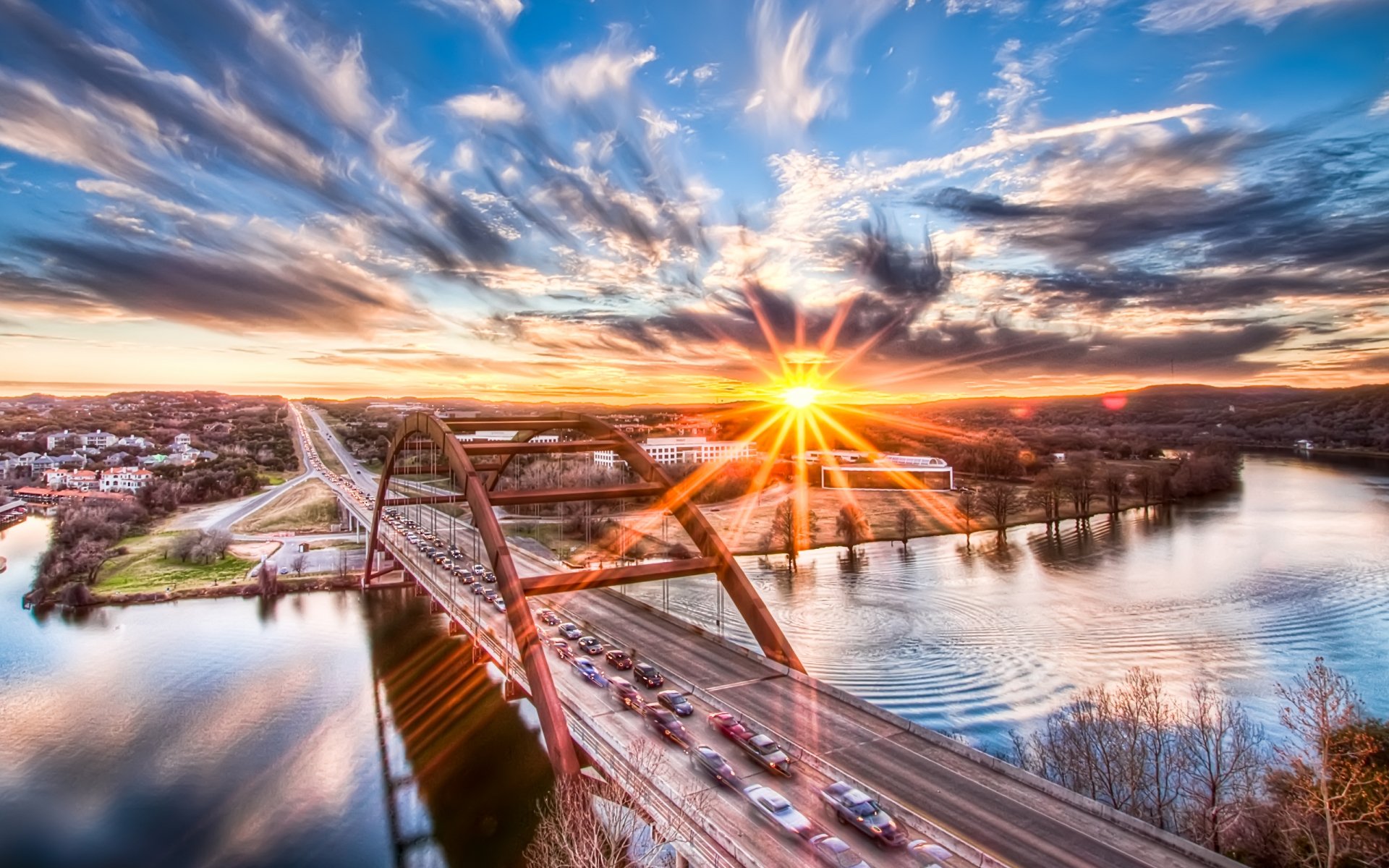 A surreal highway scene at sunset, where vibrant sun rays reflect off water, surrounded by nature, creating an artistic and captivating HD wallpaper.