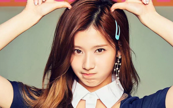 HD desktop wallpaper featuring a member of the music group TWICE with a playful expression, wearing a navy outfit and blue hairclip, hands positioned on her head.