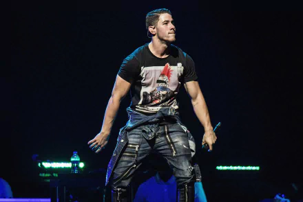 HD wallpaper featuring Nick Jonas performing on stage, showcasing his dynamic energy and style in a lively concert setting.
