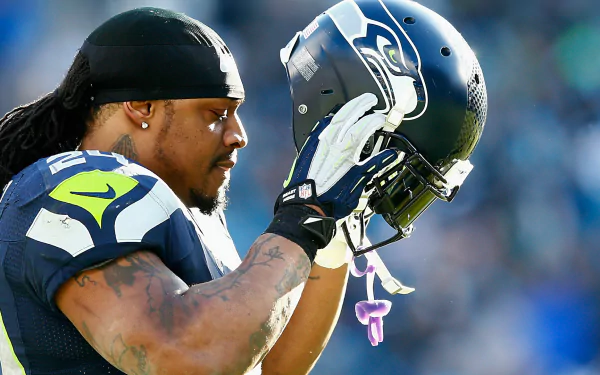 HD desktop wallpaper featuring Marshawn Lynch of the Seattle Seahawks holding his helmet.