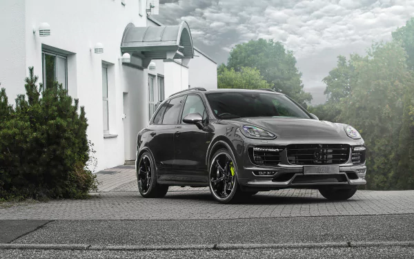 A silver Porsche Cayenne SUV parked in front of a white building under a cloudy sky, captured in high-definition for a PC desktop wallpaper.
