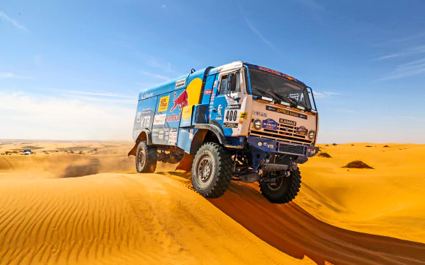 A Red Bull Kamaz rally truck racing across golden sand dunes under a clear blue horizon in a desert, captured in high-resolution 4K Ultra HD.