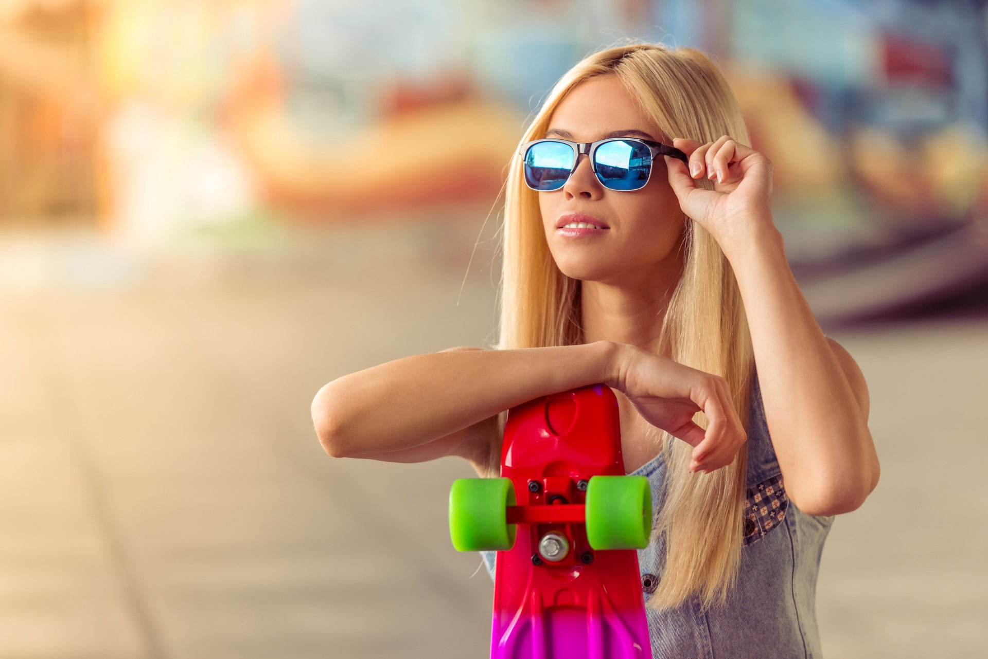 4K Ultra HD PC desktop wallpaper and background: blonde woman model in sunglasses holding a pink skateboard, shallow depth-of-field urban scene.