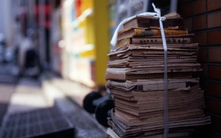 A stack of old books tied with string sits outdoors, showcasing textured paper and a vibrant urban backdrop, making it a captivating HD desktop wallpaper.