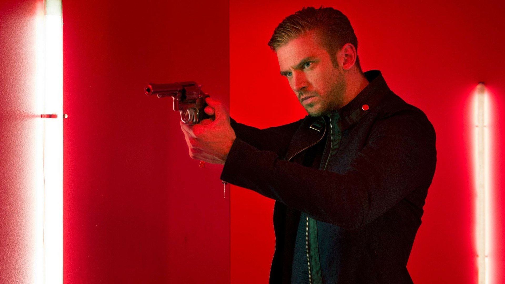 HD wallpaper with a focused man (Dan Stevens) holding a gun, backlit by dramatic red lighting.