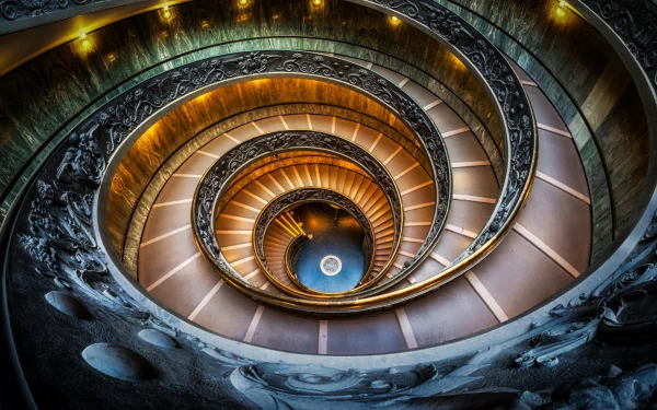 HD desktop wallpaper showcasing a man-made architectural spiral staircase with intricate railings and warm lighting, viewed from above in a striking downward perspective.