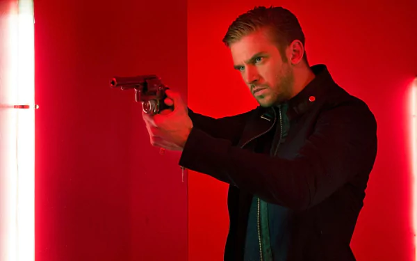 HD wallpaper with a focused man (Dan Stevens) holding a gun, backlit by dramatic red lighting.
