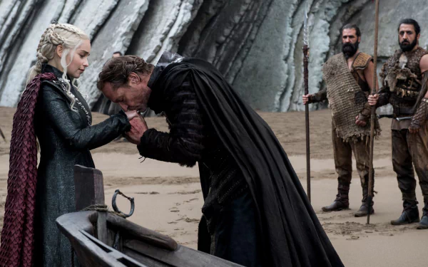 HD PC desktop wallpaper: Scene from TV show Game of Thrones — Jorah Mormont kneels and kisses Daenerys Targaryen’s hand on a windswept beach as guards stand behind.