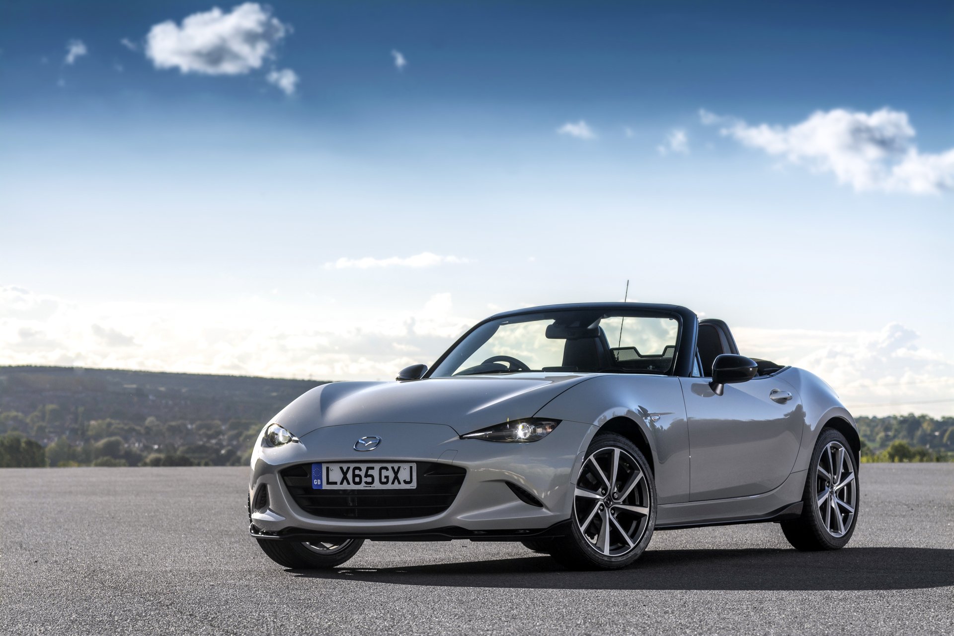 White Mazda MX-5 convertible sports car parked on a road, showcased in a sharp 4K Ultra HD wallpaper with a clear sky and scenic background.