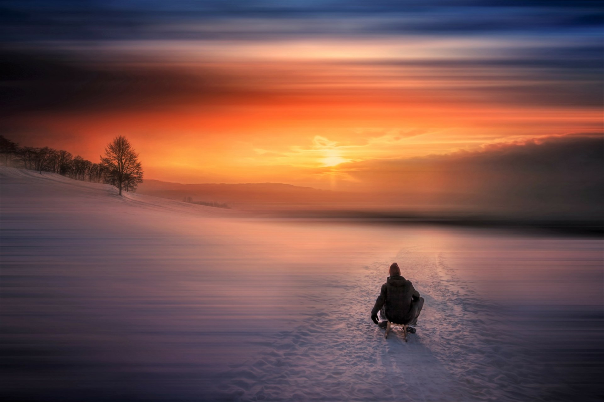 A person sledding on snow near a lake under a vibrant winter sunset sky, captured in stunning 4K Ultra HD photography.