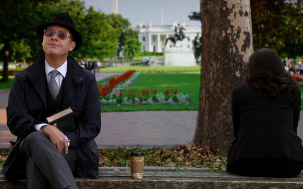 HD PC desktop wallpaper from the TV show The Blacklist, featuring a man in a hat and sunglasses sitting on a park bench with a coffee cup and book.