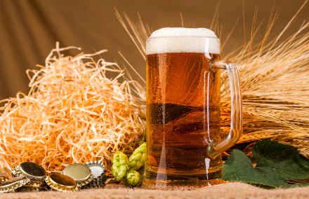 A glass of beer with foam, surrounded by hops, barley, bottle caps, and straw, captured in an 8K Ultra HD still life composition as a PC desktop wallpaper.
