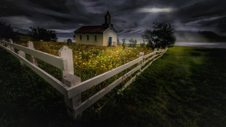 Dark storm clouds gather over a small chapel surrounded by a white fence and blooming flowers in this HD PC desktop wallpaper.