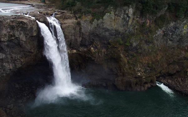 HD PC desktop wallpaper of Snoqualmie Falls: a powerful waterfall dropping into an emerald pool framed by mossy cliffs and evergreen forest.