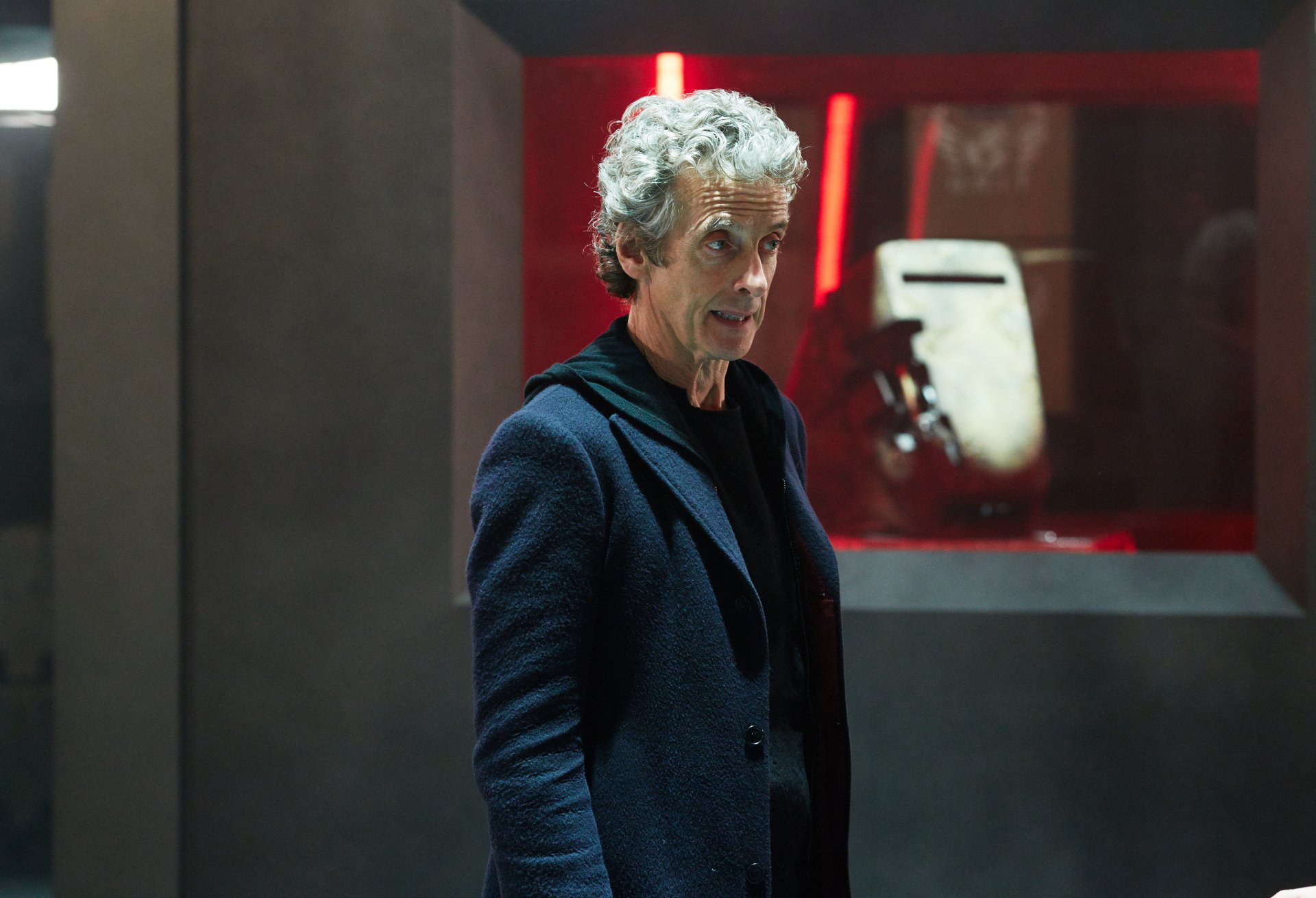 Silver-haired man in a dark coat stands in a red-lit sci‑fi interior from Doctor Who (2005) TV show — 4K Ultra HD PC desktop wallpaper and background.