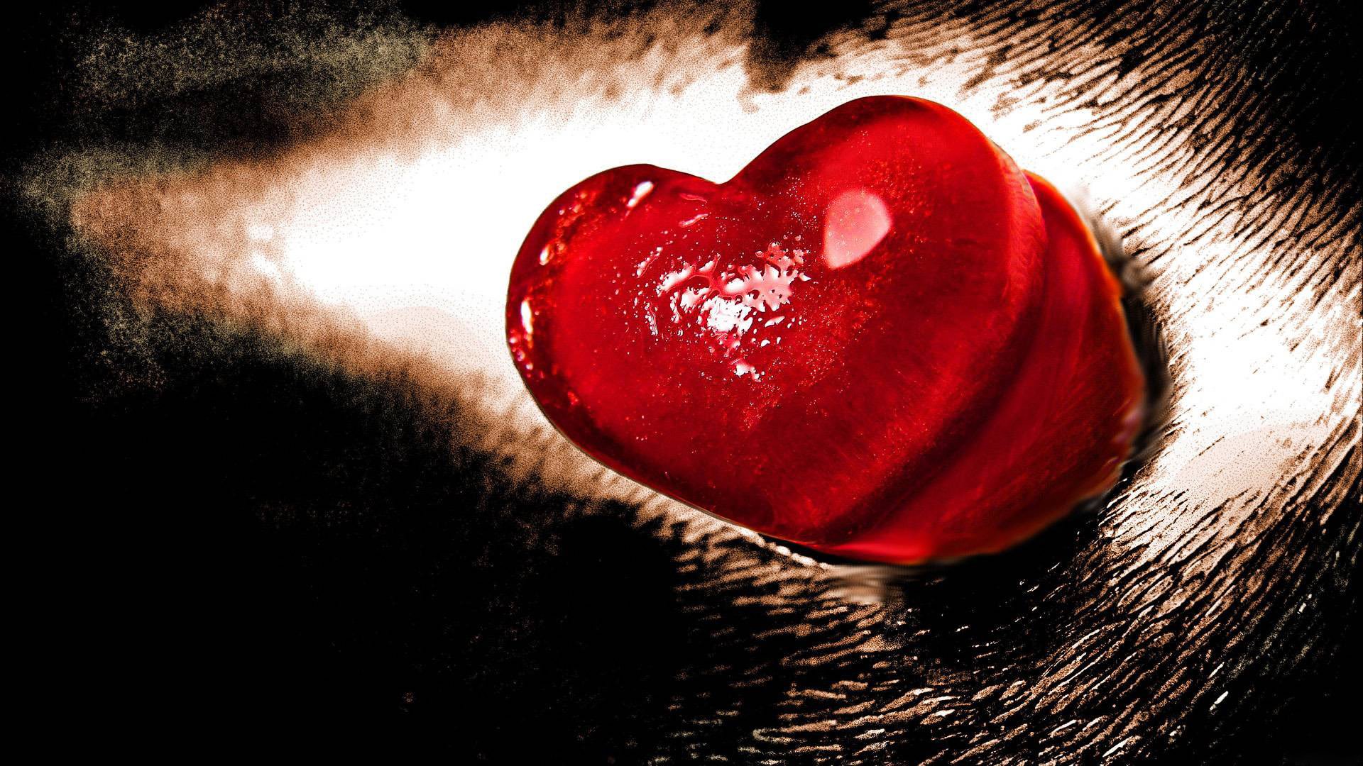 A striking artistic image of a glossy red heart set against a dark backdrop, capturing the essence of love. This HD desktop wallpaper adds a passionate touch to any screen.