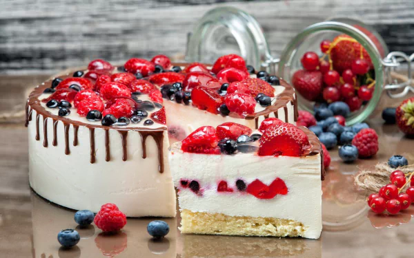 HD desktop wallpaper of a creamy cheesecake topped with strawberries, raspberries, blueberries, and chocolate drizzle, surrounded by fresh berries on a rustic wooden surface.