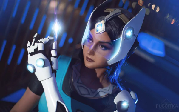 HD PC desktop wallpaper: woman cosplaying Symmetra from Overwatch, close-up with glowing headpiece and hand light construct against a blue futuristic background.