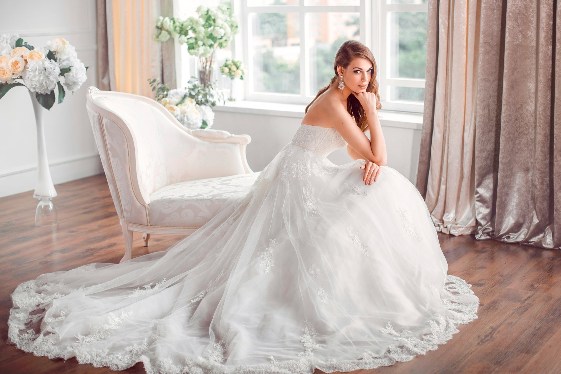 Blonde, blue-eyed bride model in a flowing white wedding dress seated in an airy room — 5K Ultra HD PC desktop wallpaper background.