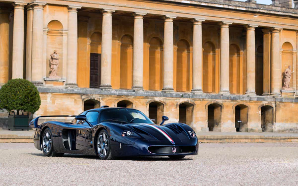 A sleek black Maserati MC12 supercar parked in front of a historic building with classical columns, captured in high definition for a PC desktop wallpaper.