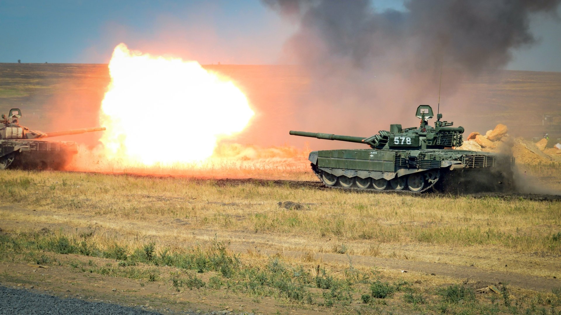 A T-72 military tank firing its cannon in a grassy field, captured in stunning 4K Ultra HD quality for a desktop wallpaper.