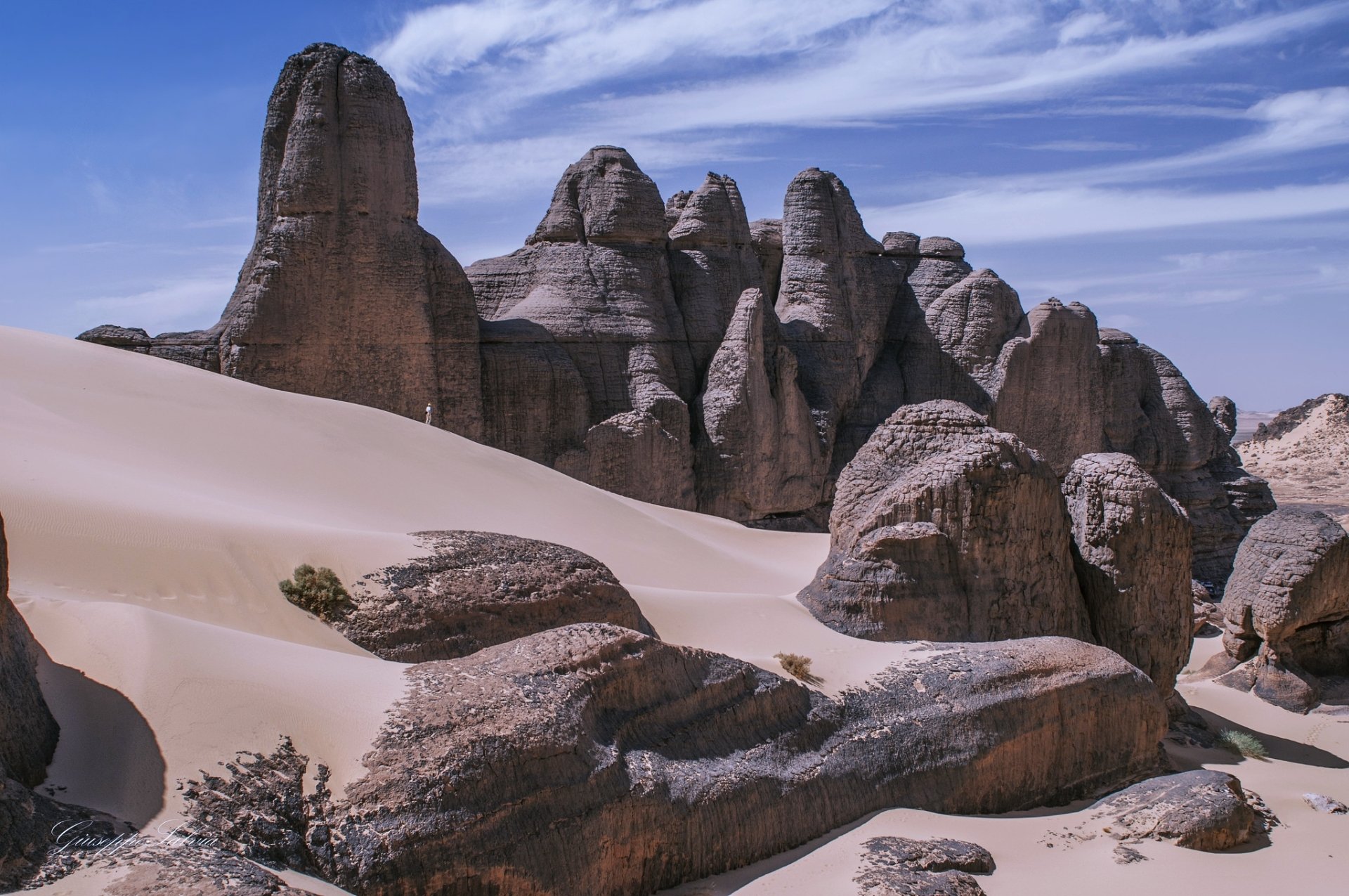 HD desktop wallpaper showcasing the sand dunes and rocky formations of Tadrart in Tassili N'Ajjer National Park, Sahara Desert, Algeria, Africa.
