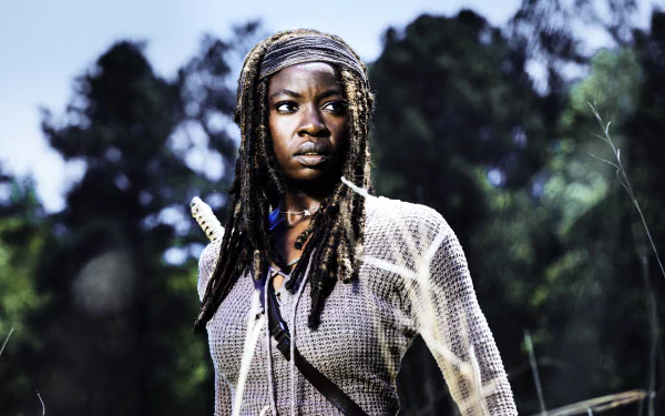 Michonne, portrayed by Danai Gurira in The Walking Dead, stands confidently in a lush background, showcasing her strength and determination in this stunning 4K Ultra HD wallpaper.