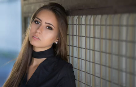 A brunette woman with long hair and brown eyes poses against a tiled wall in this 4K Ultra HD PC desktop wallpaper and background.