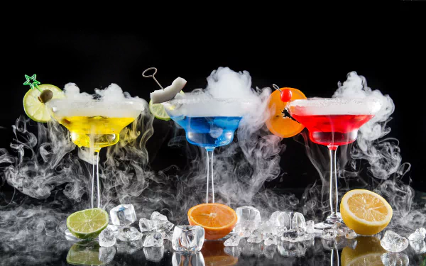 Three vibrant cocktails in yellow, blue, and red, adorned with fruit and smoky effects, sit on ice cubes. A striking 4K Ultra HD background enhances the drink's lively appeal.