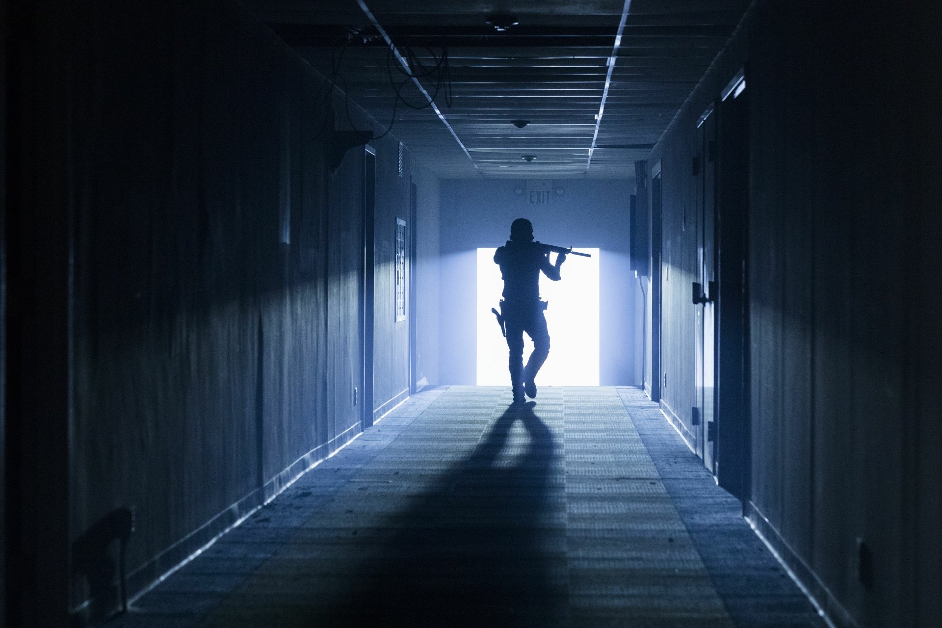 Silhouette of Rick Grimes, played by Andrew Lincoln, walking down a dim hallway, holding a rifle, from the TV show The Walking Dead in 4K Ultra HD quality.