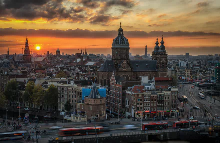 HD desktop wallpaper showcasing Amsterdam’s cityscape at sunset, featuring historic buildings and vibrant skies in the Netherlands.