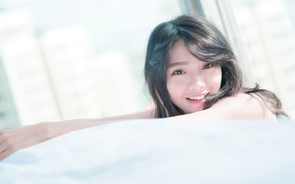 A smiling Asian woman lying down, captured in a bright, high-definition image suitable as a desktop wallpaper.