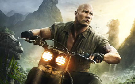 HD desktop wallpaper featuring Dwayne Johnson from the movie Jumanji: Welcome to the Jungle, riding a motorcycle through a jungle landscape with his intense expression.